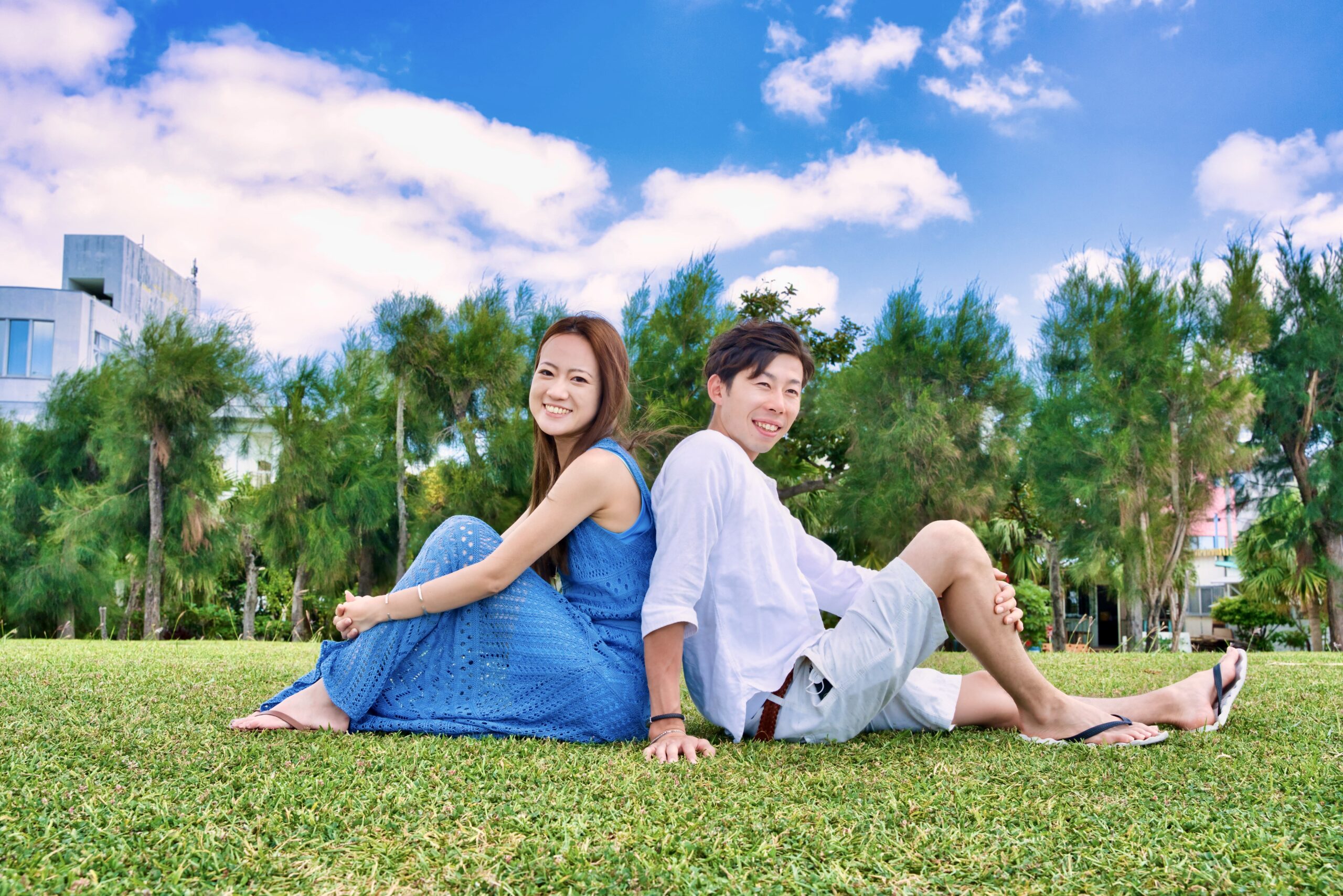 沖縄の緑あふれるロケーションで背中合わせに座るカップルフォト