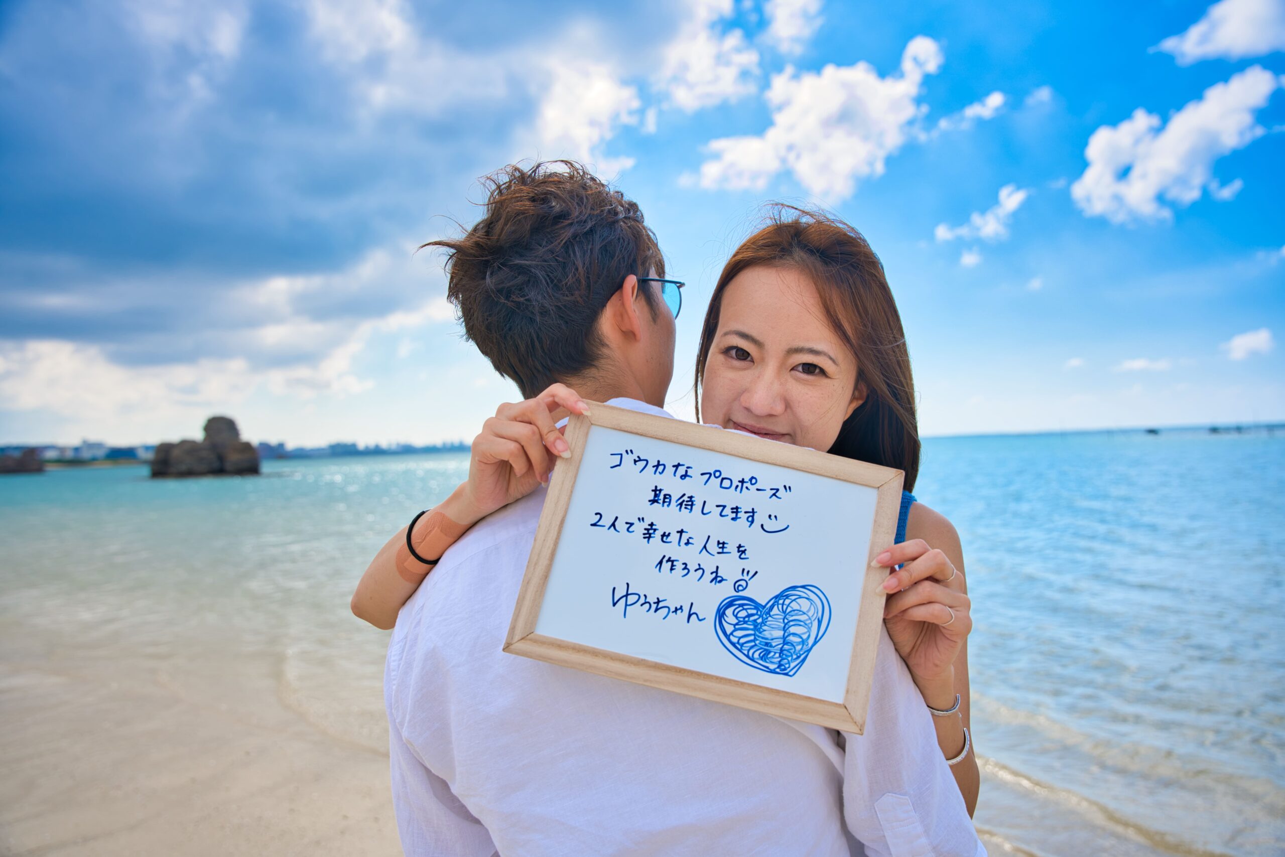 沖縄ビーチで手を繋ぐカップルフォト｜エメラルドグリーンの海と白砂の砂浜