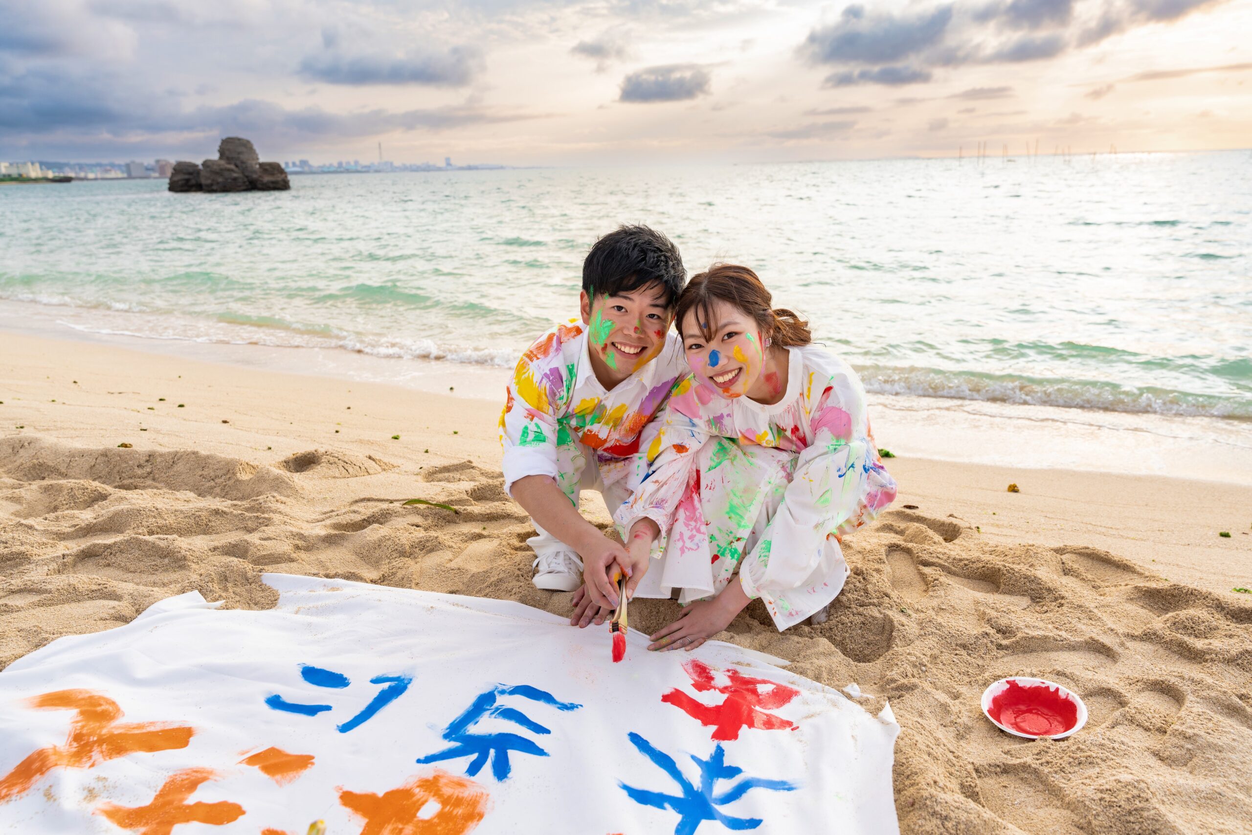 沖縄ペイントフォト｜アラハビーチで絵の具まみれのカップルが寄り添うロケーション撮影