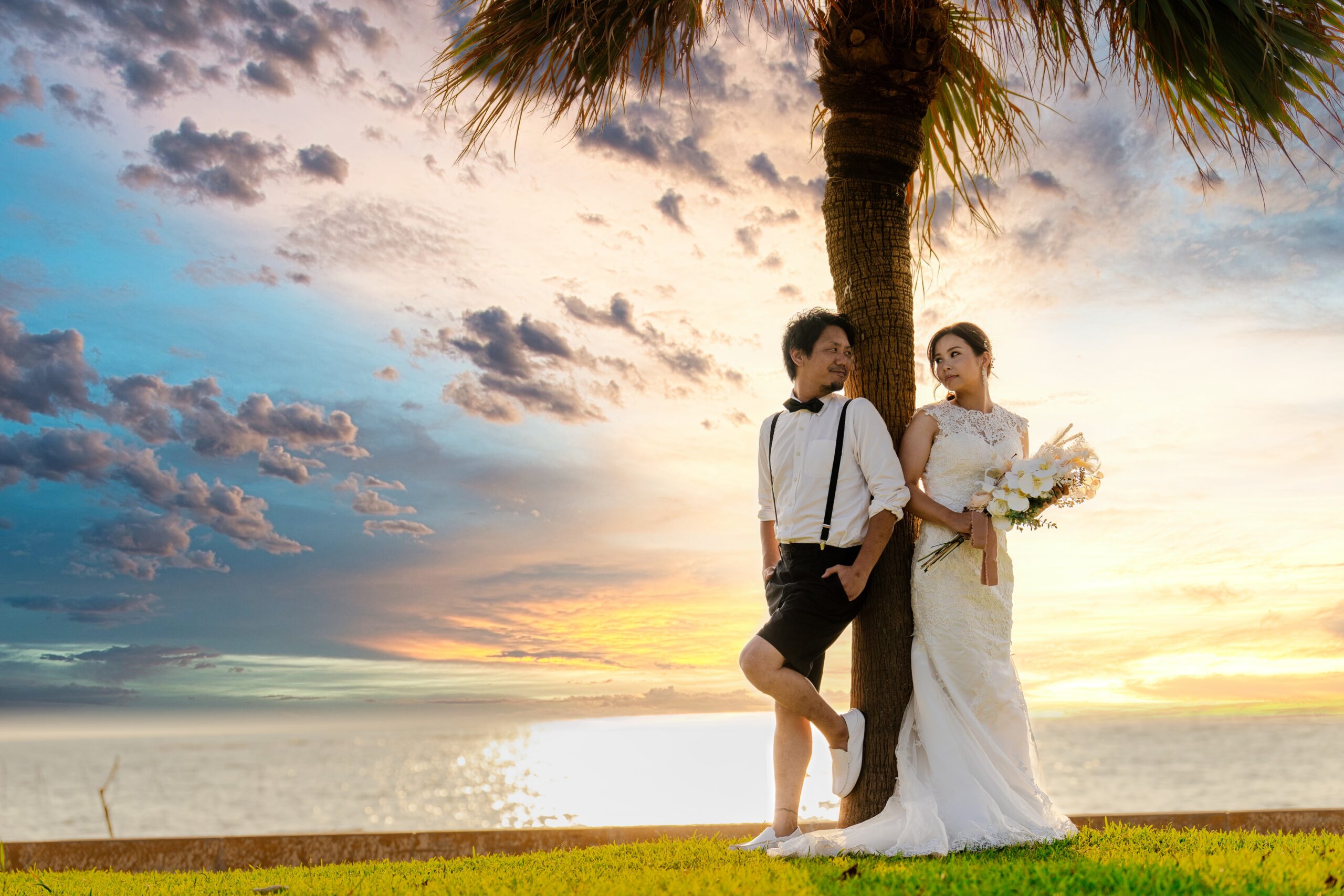 夕焼けのビーチでブーケを持つ花嫁の後ろ姿