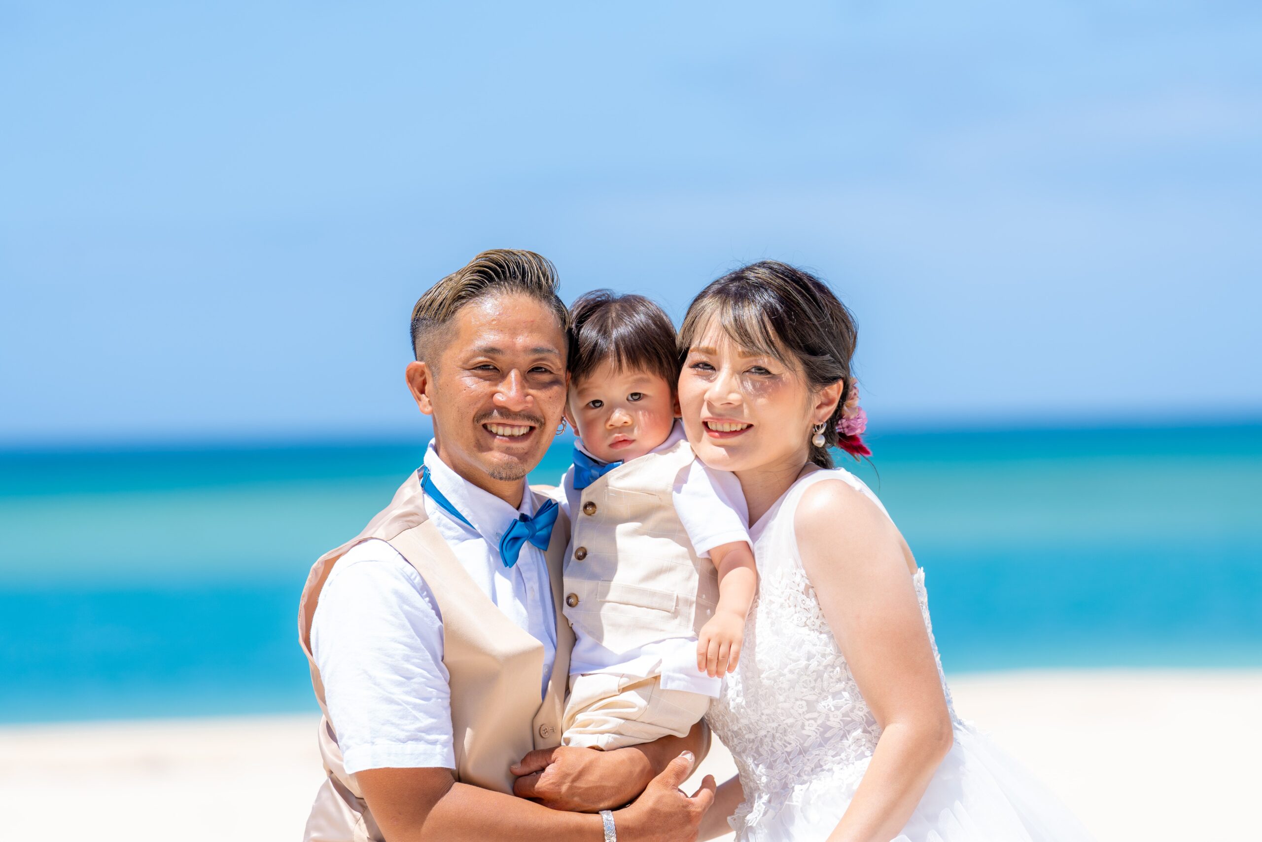 エメラルドグリーンの海辺で微笑む新郎新婦