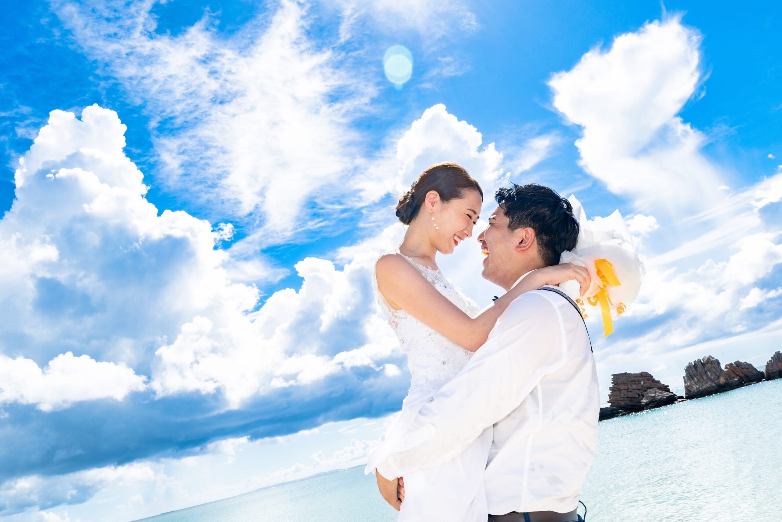 青い海と白い砂浜でポーズを取るウェディングカップル