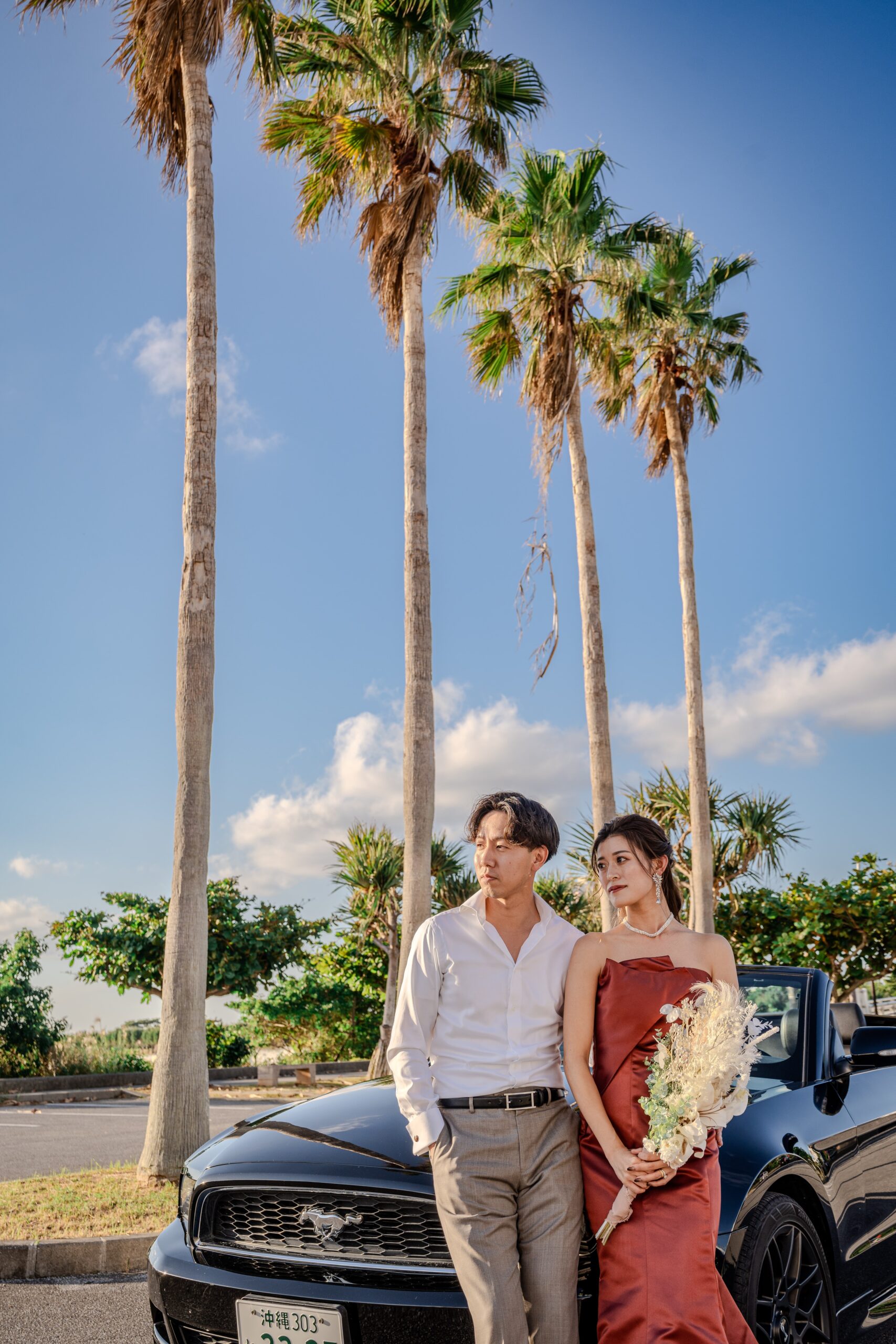 ヤシの木が並ぶ沖縄のビーチで新郎新婦のポートレート