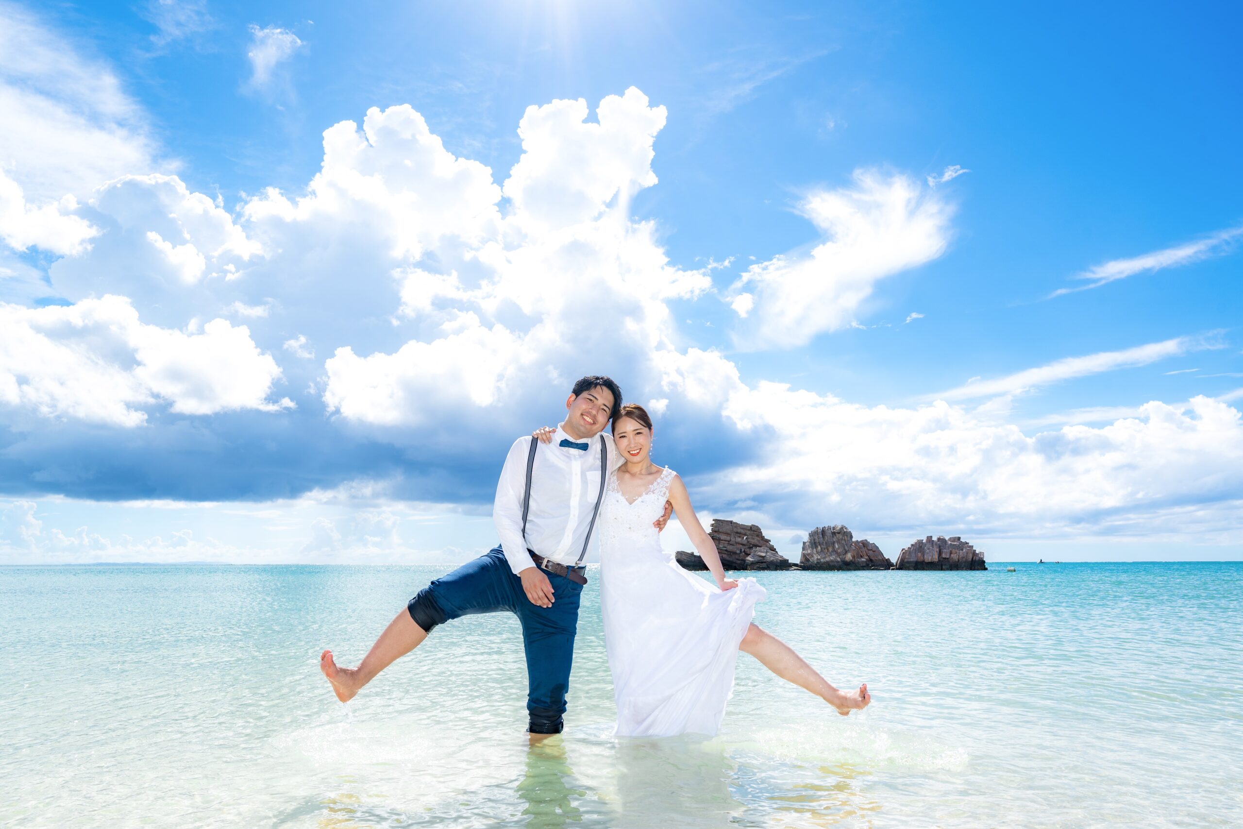 夕日に照らされたビーチで結婚指輪を見せるカップルの手元