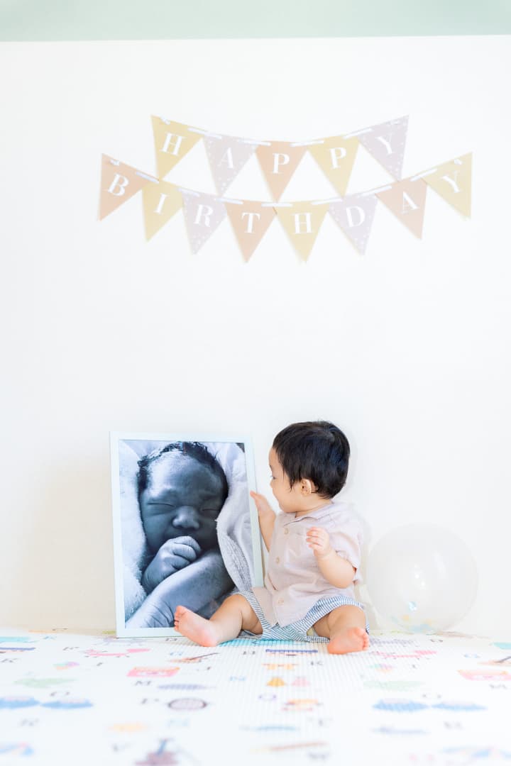 沖縄のタンカーユーエイで生まれた時の写真を見つめる1歳の子どもの成長記録フォト｜沖縄ファミリーフォト