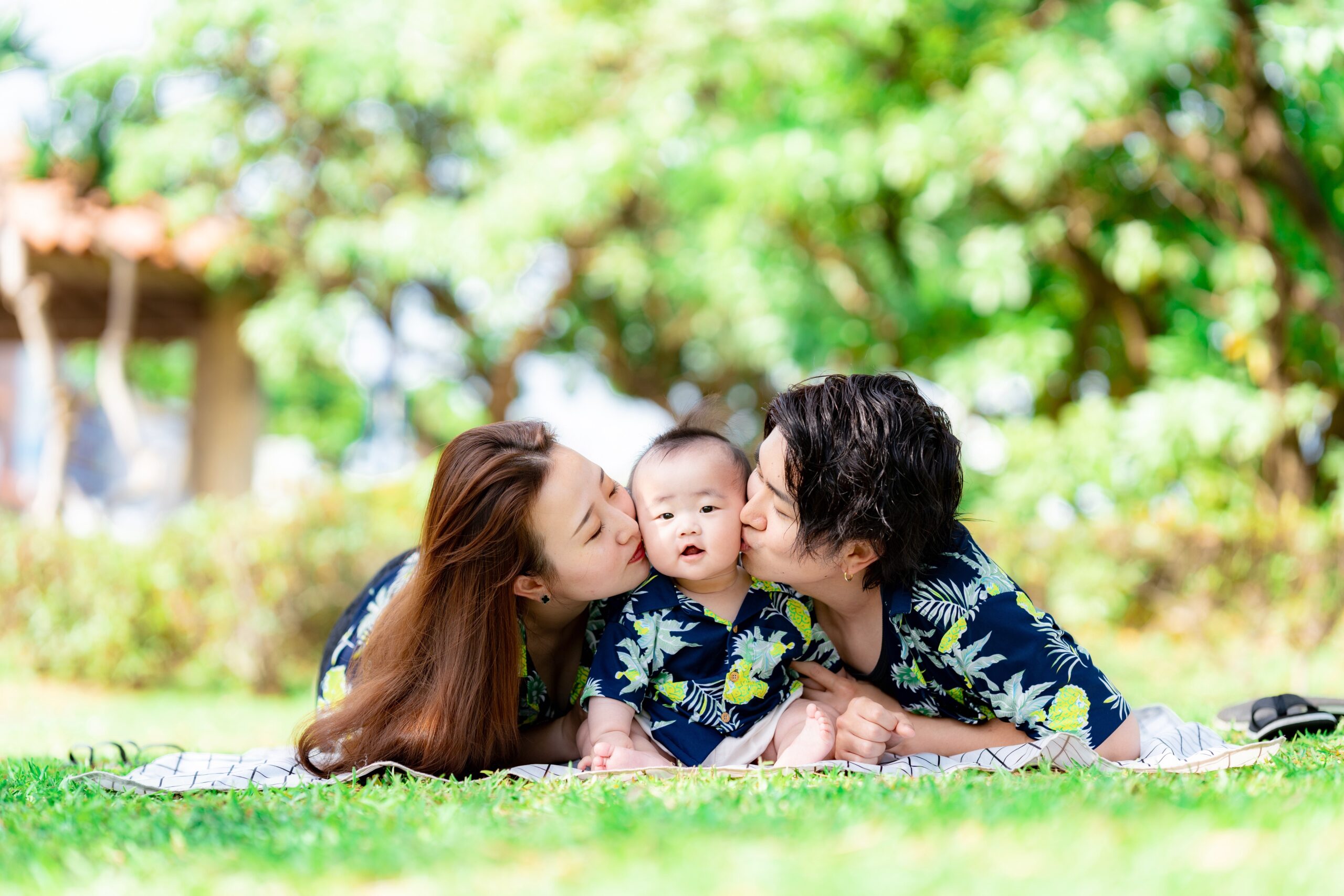沖縄の緑の中で家族3人がパパの背中に乗っかる楽しいファミリーフォト｜沖縄ビーチフォト
