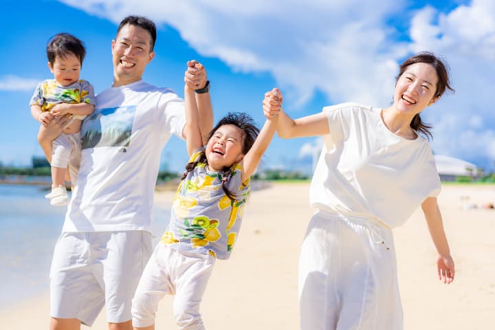 ビーチで手をつないでジャンプする家族