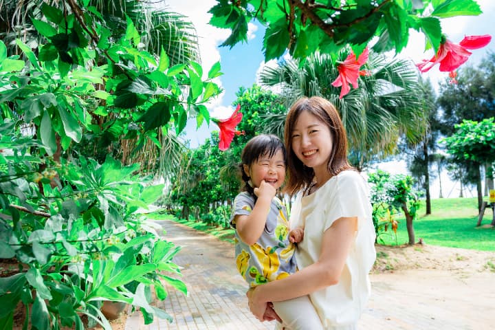 沖縄の南国植物に囲まれた温かい雰囲気のファミリーフォト｜沖縄ビーチフォト