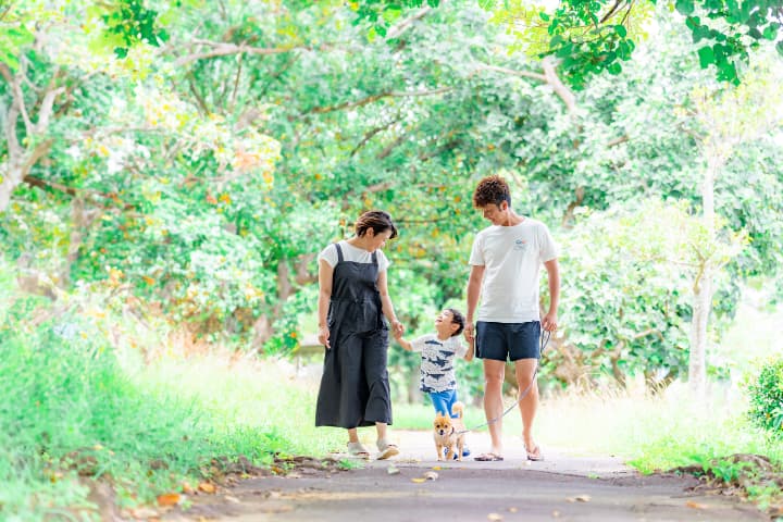 沖縄の緑あふれる道を家族みんなでお散歩する自然な家族写真｜沖縄ファミリーフォトビーチ
