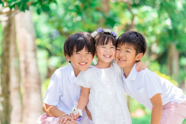 沖縄の自然の中で兄弟3人が頬を合わせて笑う可愛い家族写真｜沖縄ロケーションフォト
