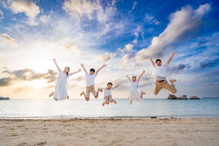 沖縄のサンセットビーチで家族全員が大ジャンプする躍動感あふれるファミリーフォト｜沖縄家族写真海