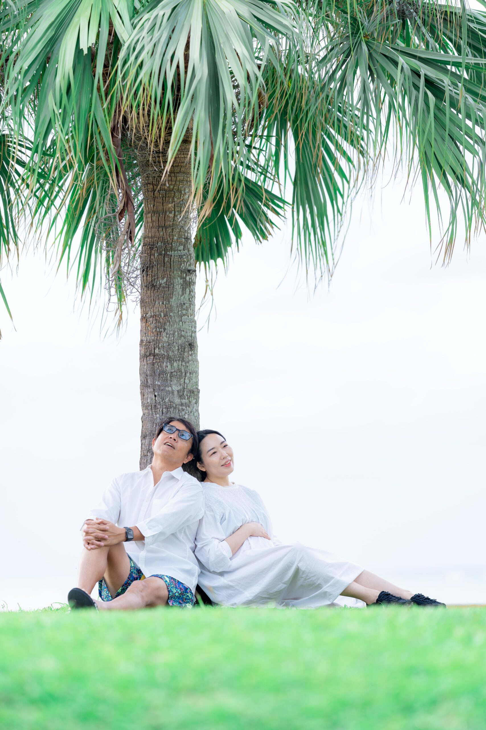 沖縄の自然に囲まれたマタニティフォト。優しく微笑む夫婦のカット。