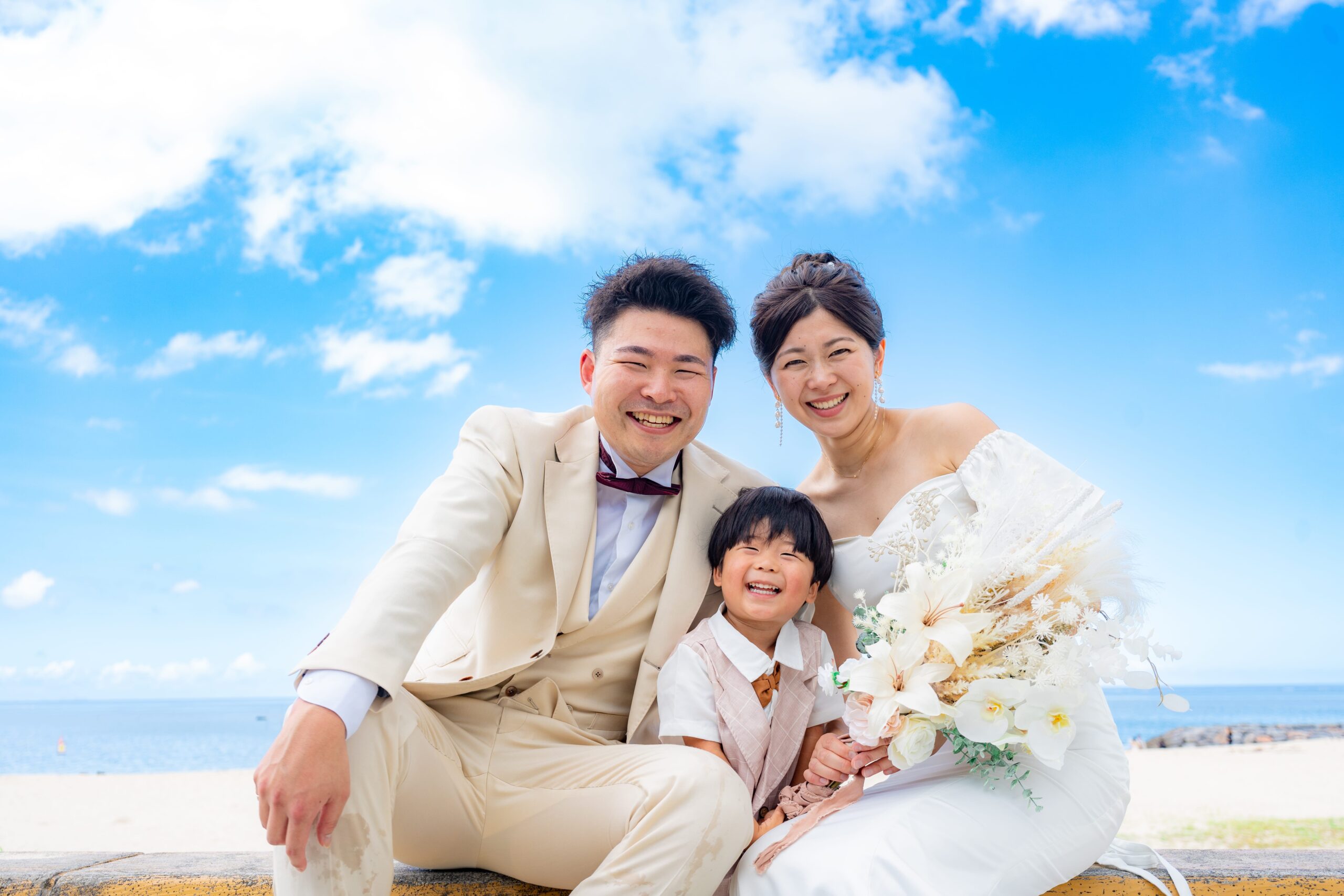 沖縄の海辺でブーケを持ち寄り添う新郎新婦