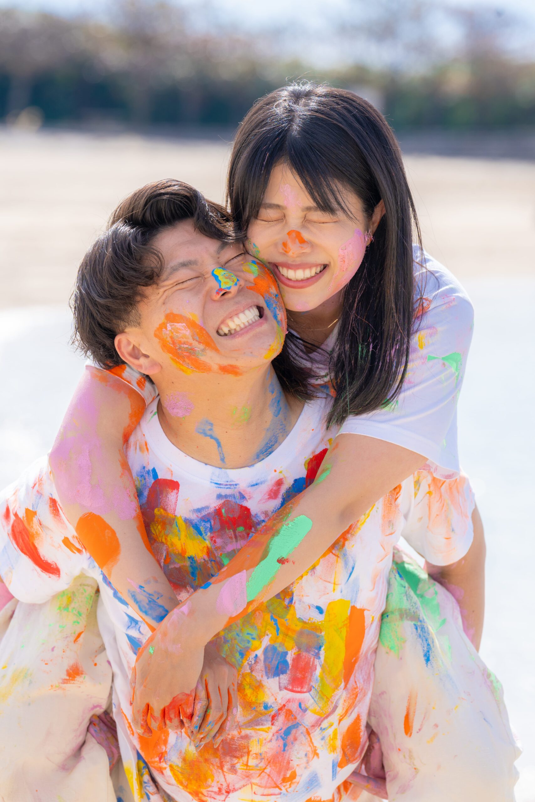 沖縄ペイントフォト｜沖縄ビーチで彼女を肩車する絵の具まみれカップルの躍動感ある一枚