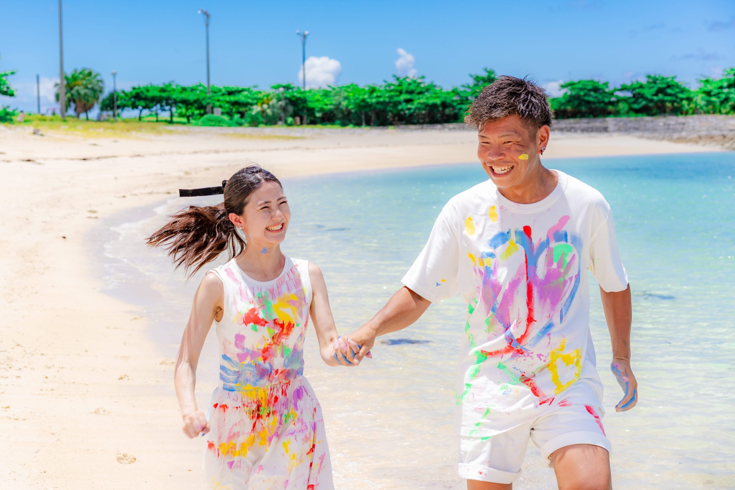 沖縄ペイントフォト｜ビーチではしゃぎながら絵の具を掛け合うカップルの自然な笑顔