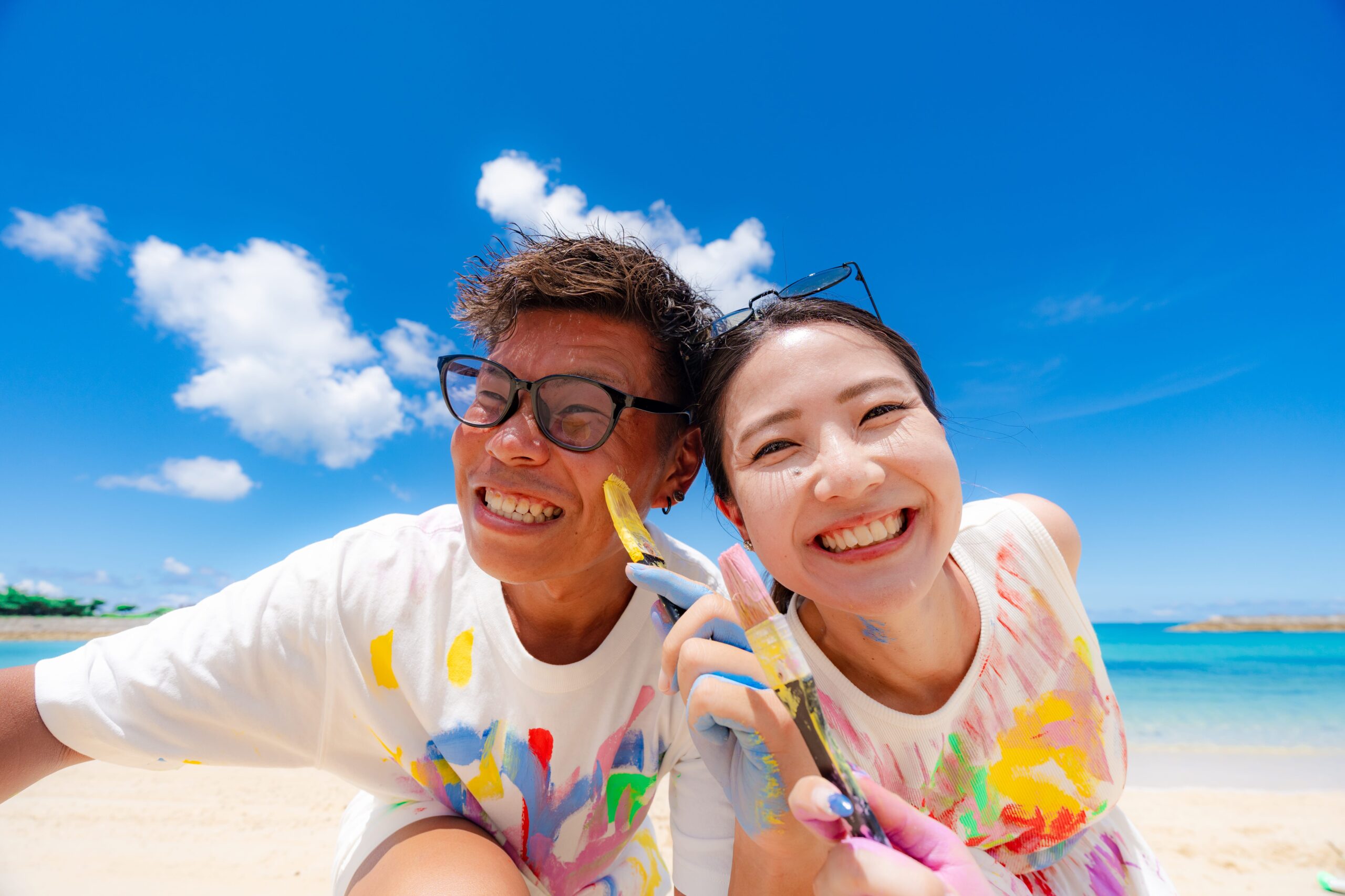 沖縄ペイントフォト｜カメラに近寄って大笑いするカップルの臨場感あるペイント撮影