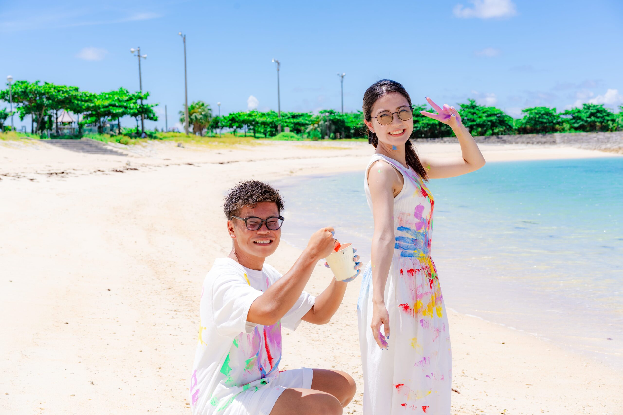 沖縄ペイントフォト｜エメラルドグリーンの海を背景に絵の具を塗り合うカップル