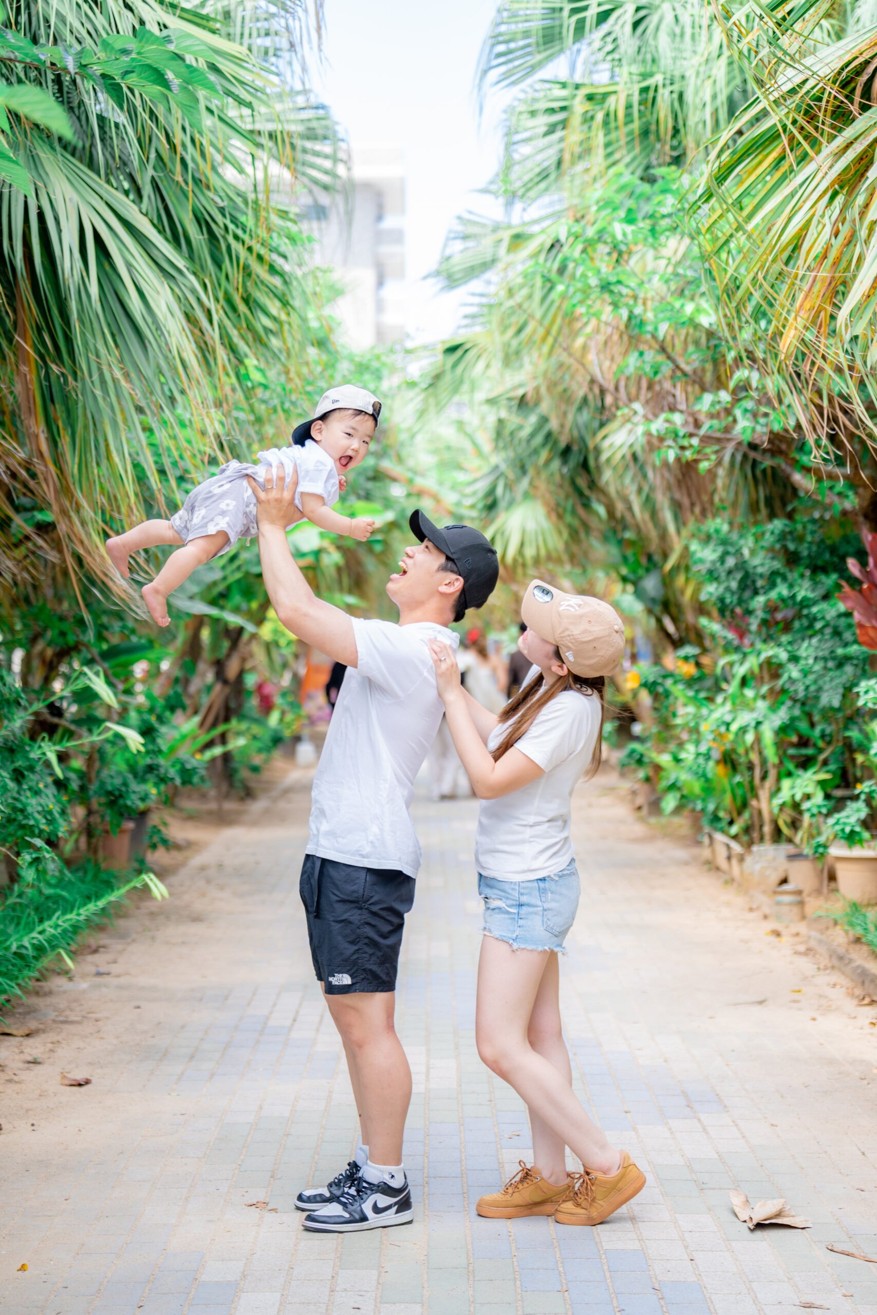 沖縄の緑豊かなロケーションでパパが子どもを高い高いするファミリーフォト｜沖縄家族写真ビーチ