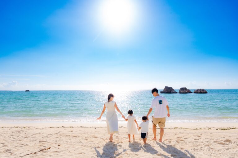 沖縄のビーチで手を繋いで歩く家族4人の後ろ姿のファミリーフォト｜沖縄ビーチフォト