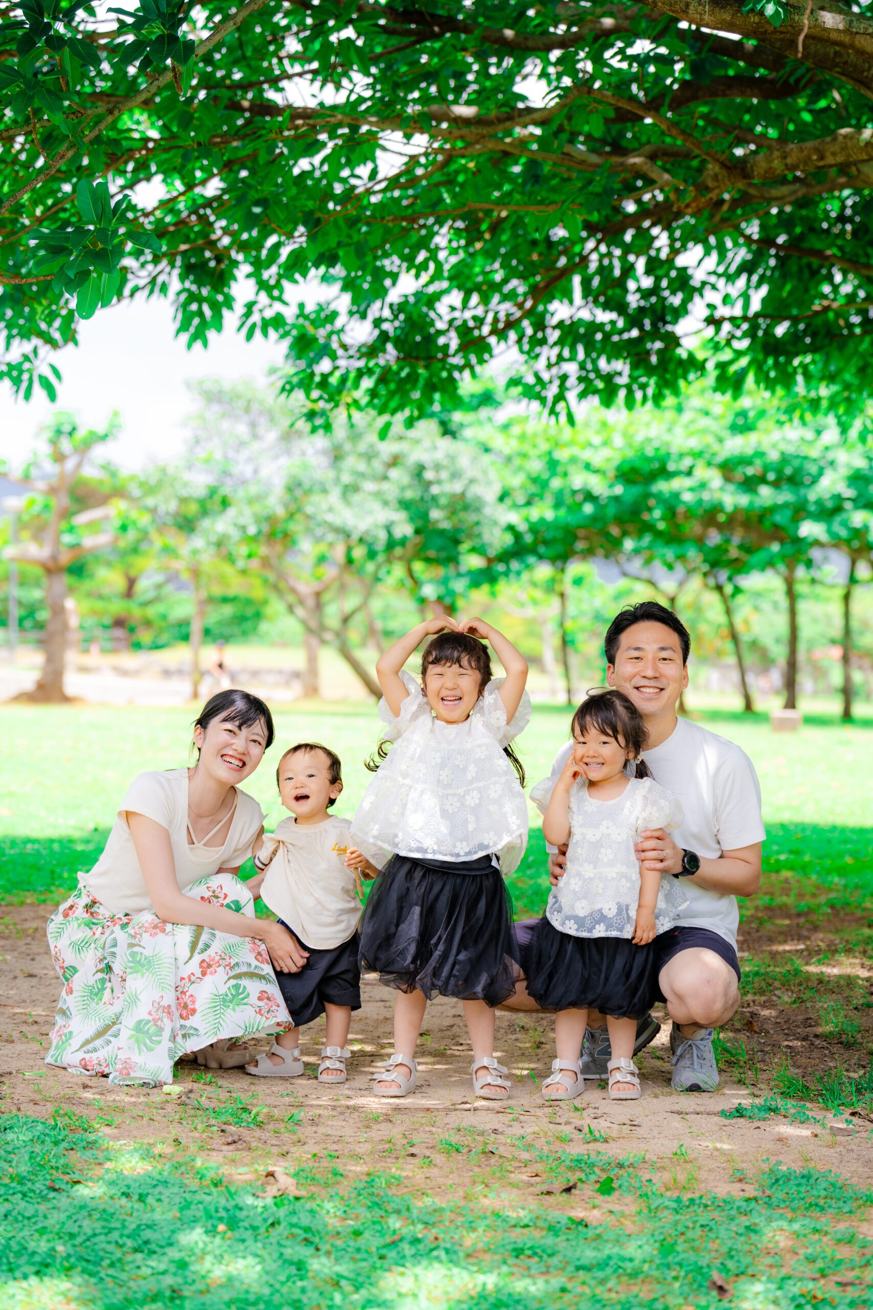 沖縄のグリーンを背景に家族5人が笑顔で撮った記念のファミリーフォト｜沖縄ファミリーフォト