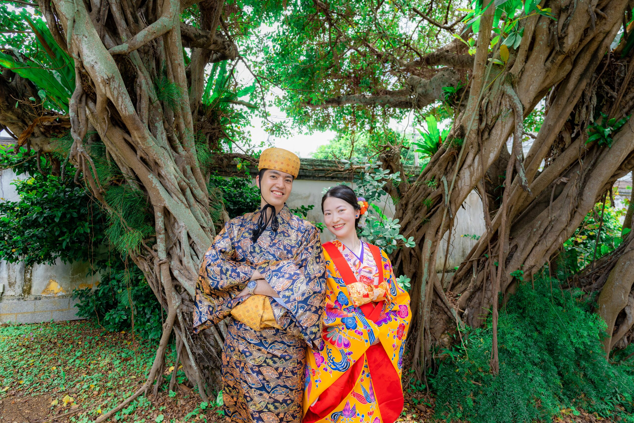 沖縄の緑豊かな高台から海を望む琉装カップル
