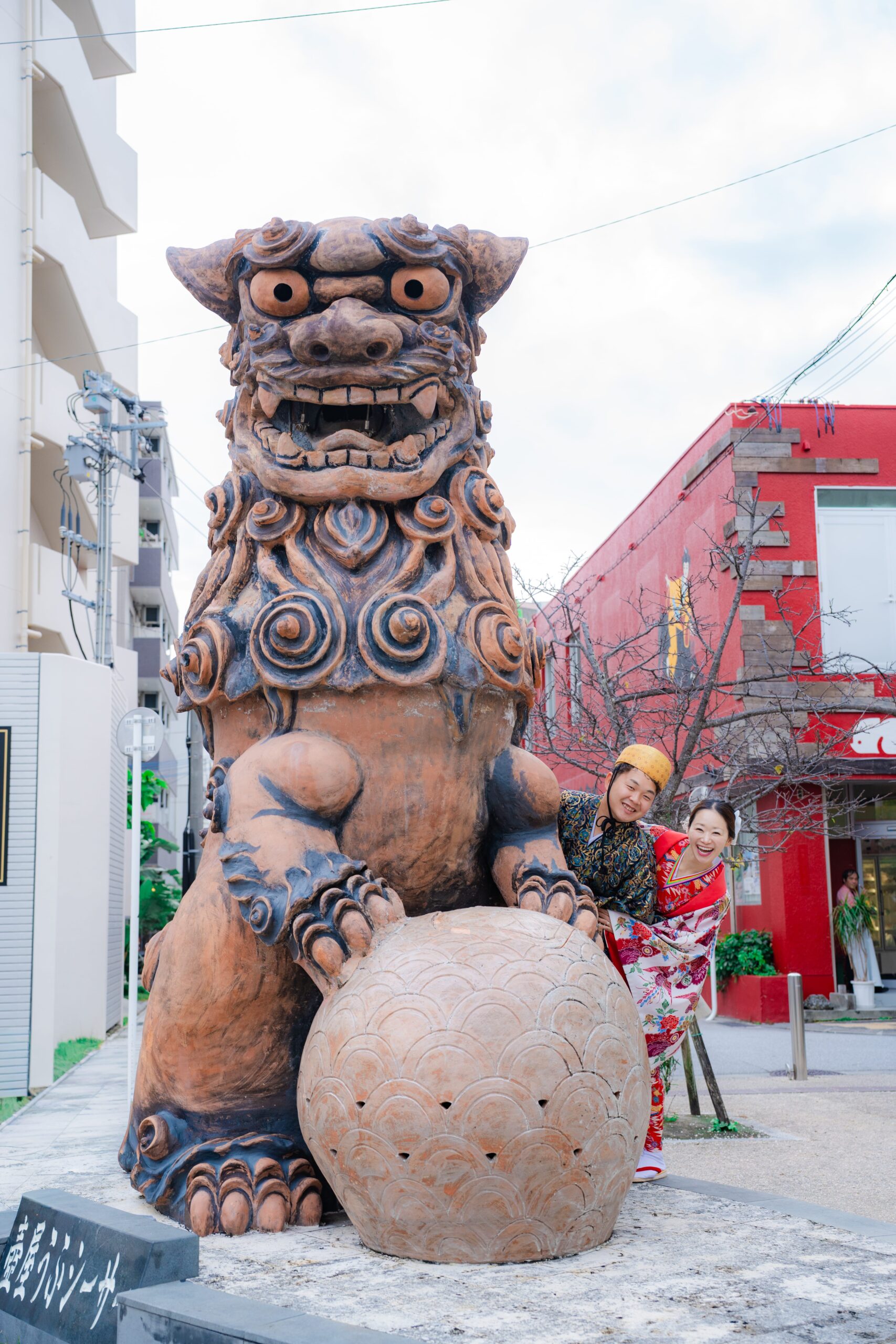 シーサーの前で紅型衣装のカップル記念写真