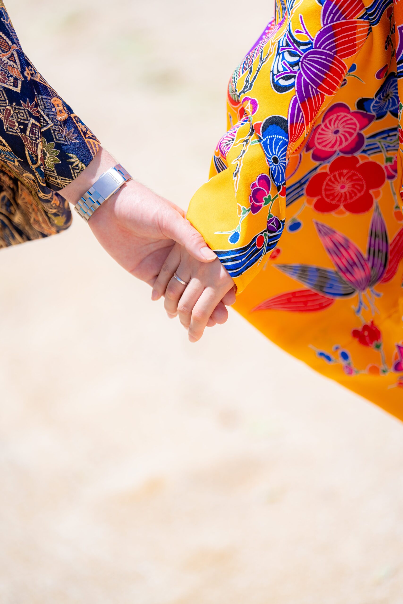 鮮やかな紅型衣装で手をつなぐカップルのクローズアップ