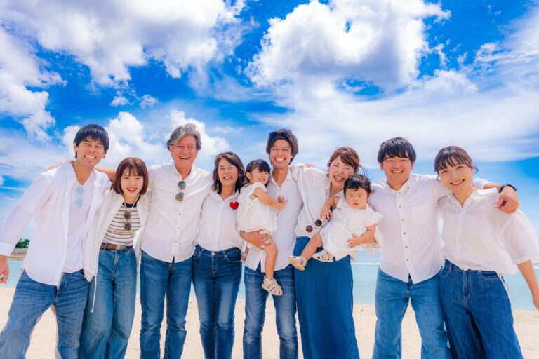 沖縄の海で60歳の還暦祝いに家族全員で肩を組んだ記念の家族写真｜沖縄還暦祝い撮影
