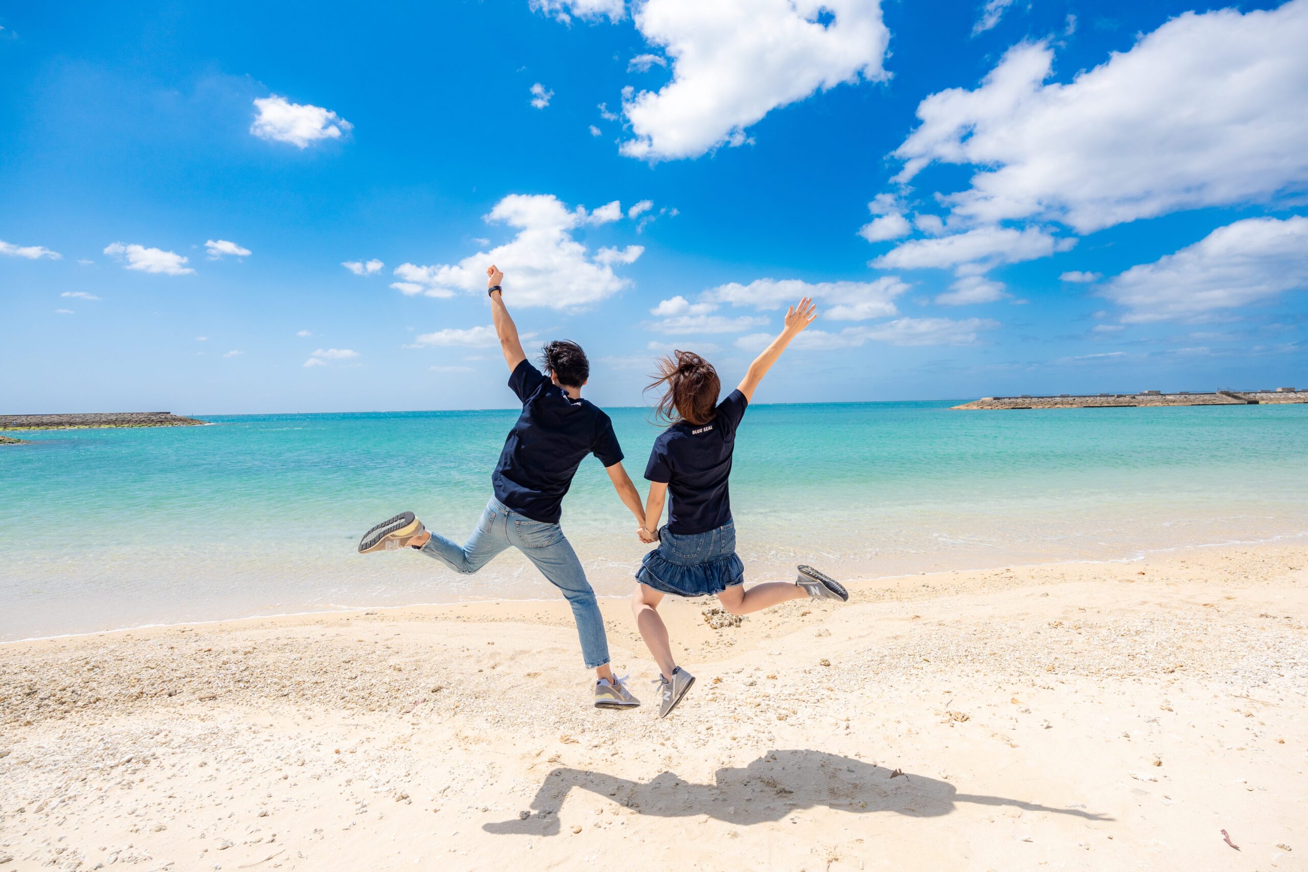 沖縄の海でジャンプするカップルフォト｜ビーチで躍動感あふれるご夫婦撮影