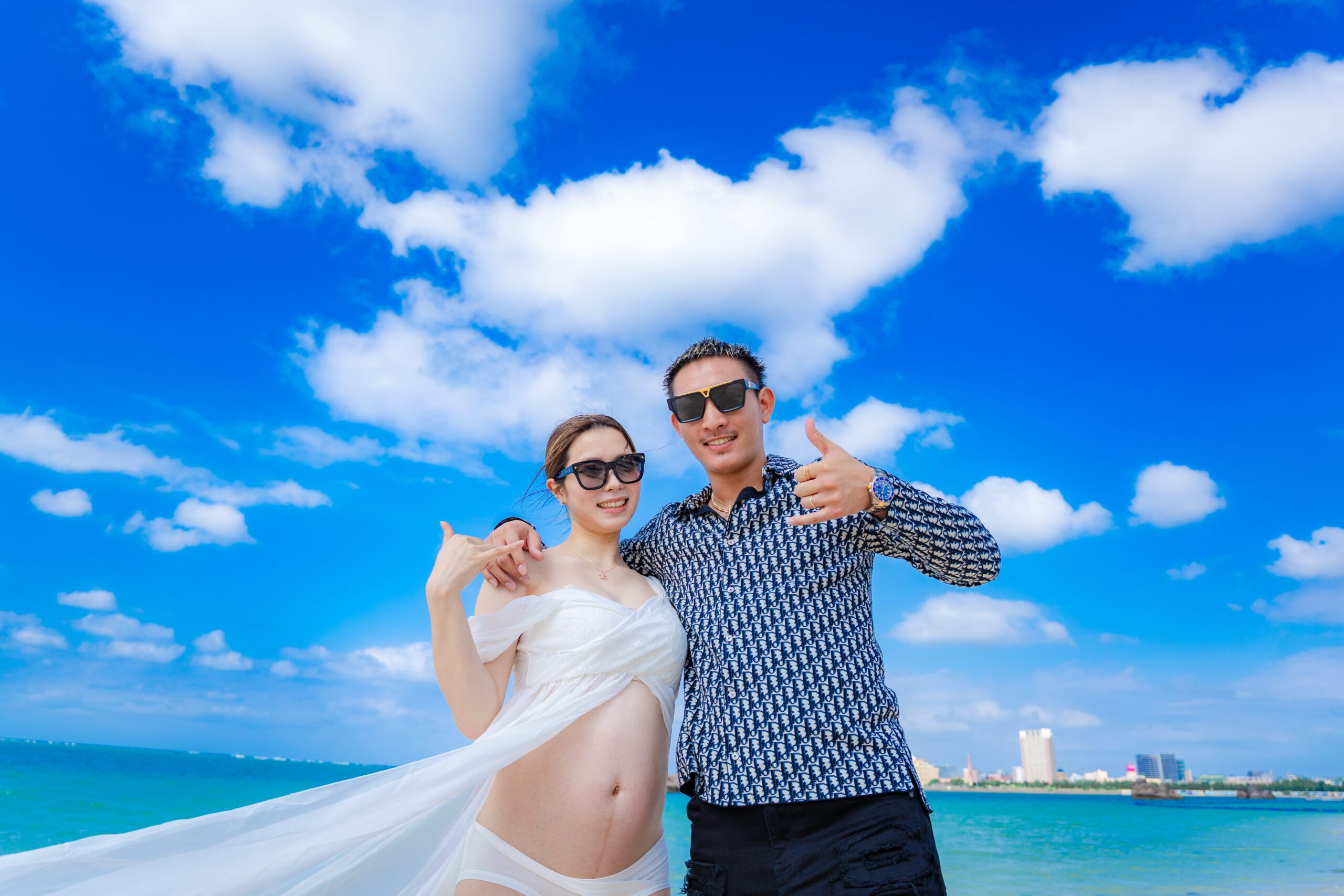 沖縄マタニティフォト｜青空が広がるビーチでポーズを決める夫婦撮影