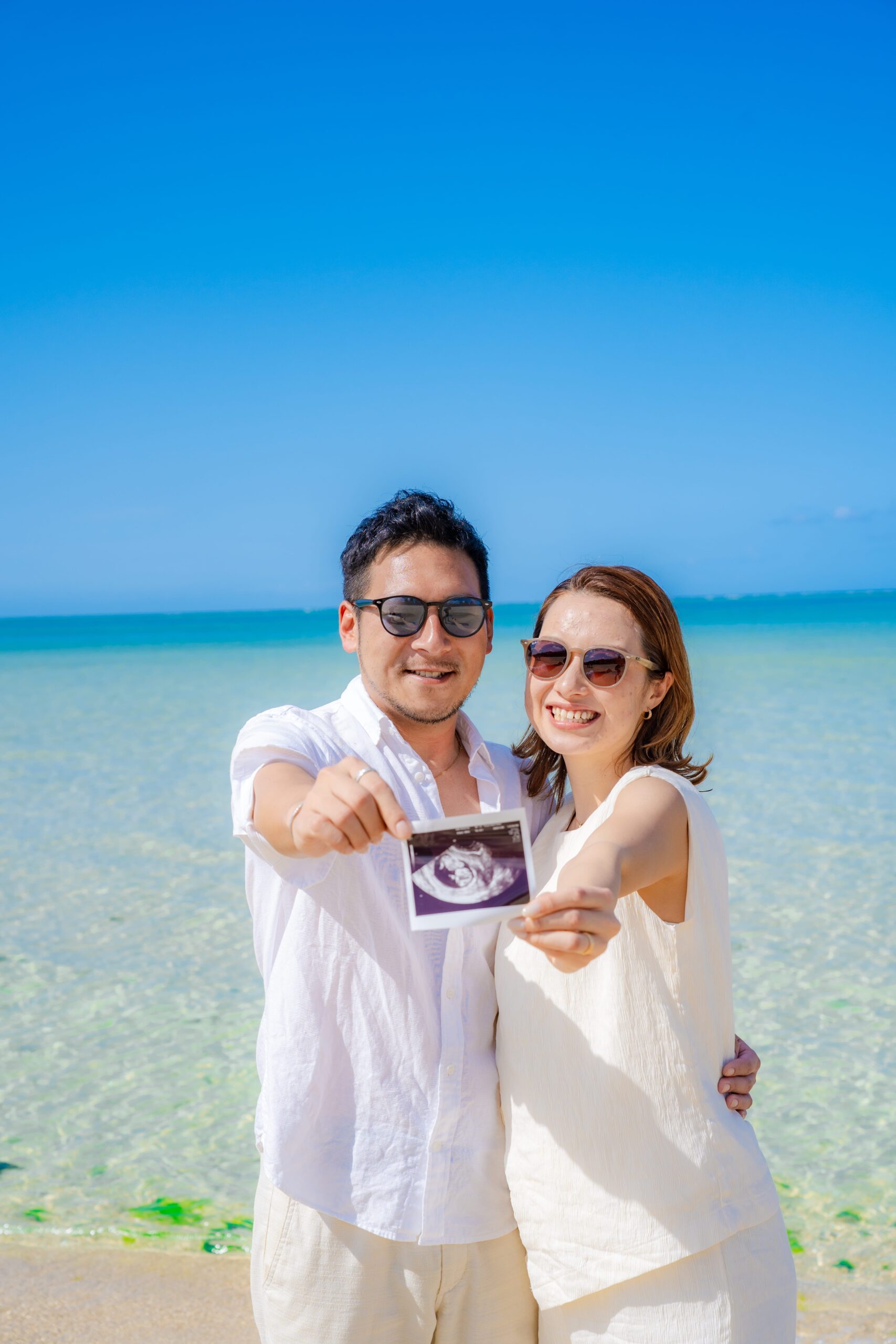 沖縄マタニティフォト｜海辺で二人でエコー写真を見つめる温かい一枚